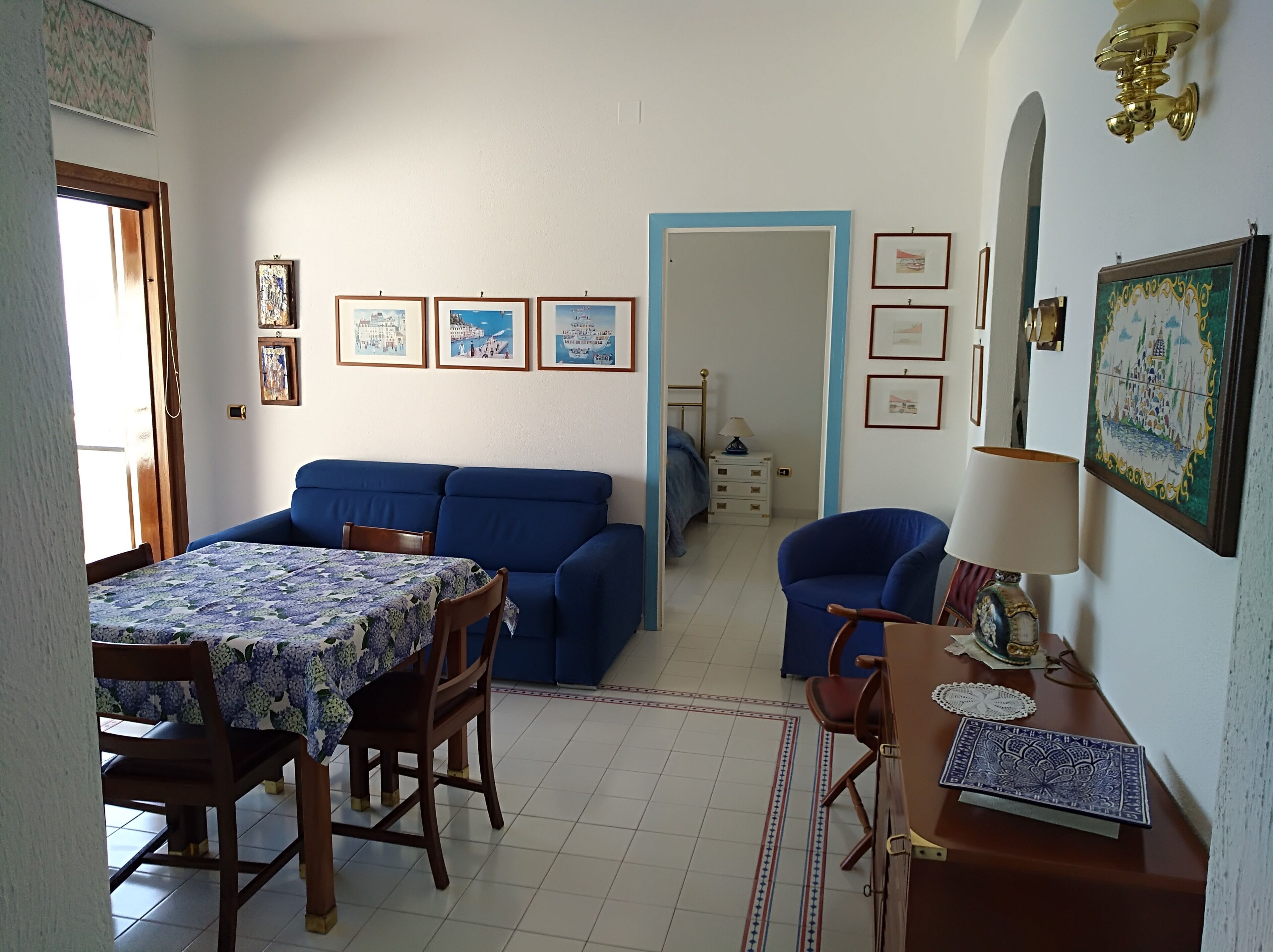 Ein Essbereich mit Tisch und Stühlen, einem blauen Sofa und einem kleinen Tisch mit einer Lampe.
