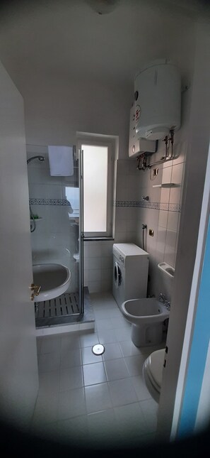 Une petite salle de bain comprenant des toilettes, un bidet et un lave-linge.