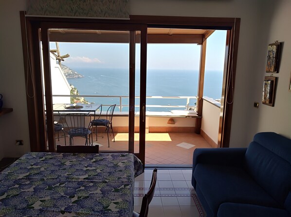 Une chambre avec un lit, un canapé bleu et un balcon donnant sur la mer.