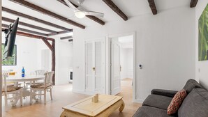 Amplia sala de estar con una mesa de centro de madera, un sofá gris y una mesa de comedor con sillas.