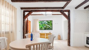 Un comedor con una mesa redonda, sillas blancas y una estructura de techo de madera.