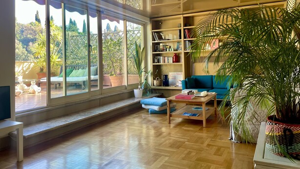 A spacious living room with a large window, a bookshelf, a blue sofa, and a coffee table. - Flaminio Penthouse with Spectacular Terrace (Roma)
