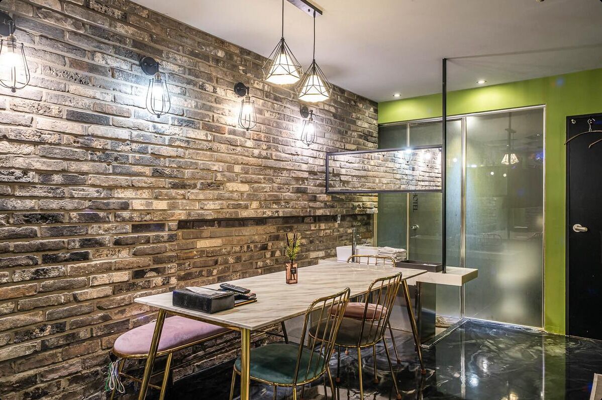 A modern dining area with a brick wall, pendant lights, a wooden table, and chairs.