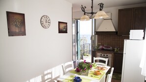 A kitchen with a dining table, chairs, a clock, and a view of the outside.