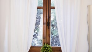 A window with white curtains, a wooden frame, and a small plant on the windowsill.