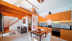 Une cuisine moderne avec des meubles en bois, un coin repas comprenant une table et des chaises, et un escalier menant à un niveau supérieur.