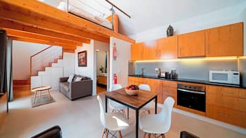 Une cuisine moderne avec des meubles en bois, un coin repas comprenant une table et des chaises, et un escalier menant à un niveau supérieur.