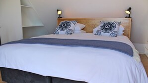 Un lit avec une tête de lit en bois, deux lampes de chevet et des coussins à motifs.