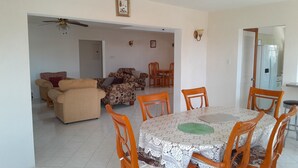 A dining area with a table and chairs, a sofa set, and a ceiling fan. - Spacious Air Conditioned 4 bed detached house near Miami Beach (Oistins)