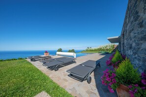 A poolside area with lounge chairs, a small pool, and a view of the ocean.