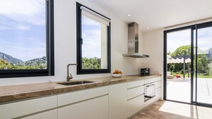 A modern kitchen with a large window, a built-in stove, and a view of the outdoors.