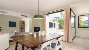 A modern dining area with a wooden table, white chairs, and a pendant light.