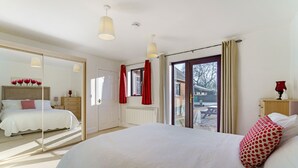 Une chambre avec un grand lit, un miroir, une commode et une vue sur l’extérieur.