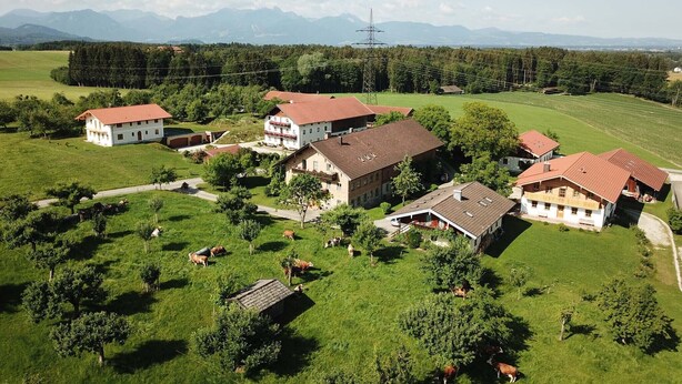 A rural property with multiple buildings, including a large house and several smaller structures, surrounded by green fields and trees. - Ferienwohnung Kampenwand, 55 qm Obergeschoss, 2 separate Schlafzimmer (Riedering)