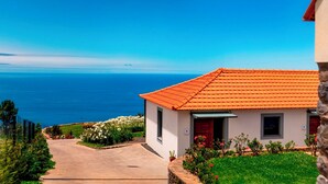 A house with a red tiled roof, a paved driveway, and a view of the sea. - In peaceful Prazeres | Qta. Inácia Hibiscus Studio (Prazeres)