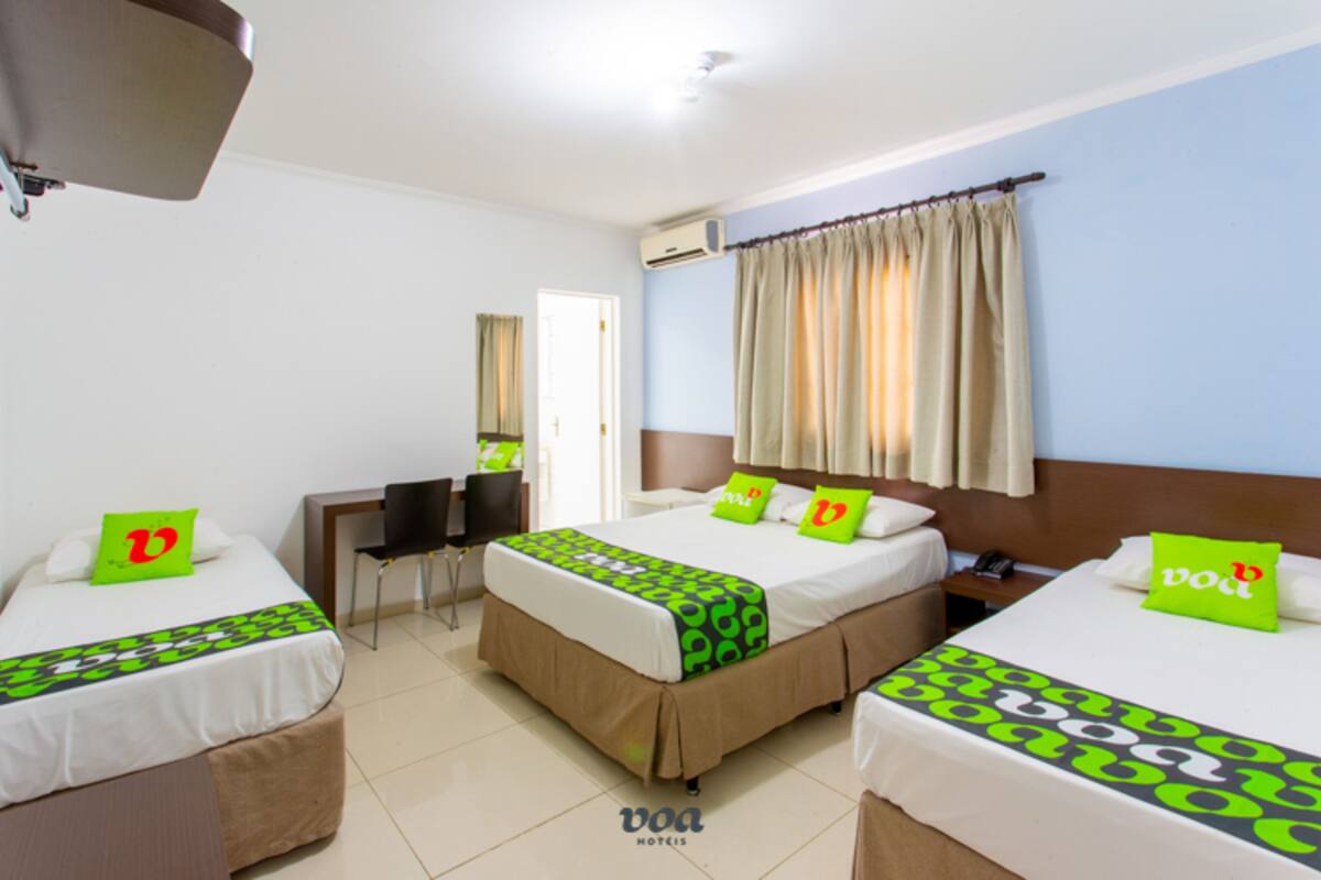 A hotel room with two beds, a desk, and a chair.