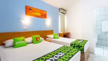 Habitación de hotel con dos camas, cada una con cubrecama verde y negro, cabecero de madera y unidad de aire acondicionado mural.