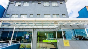 A modern hotel entrance with a glass facade, a covered entrance area, and a sign indicating room availability. - VOA Convenience Hotel (Jundiai)