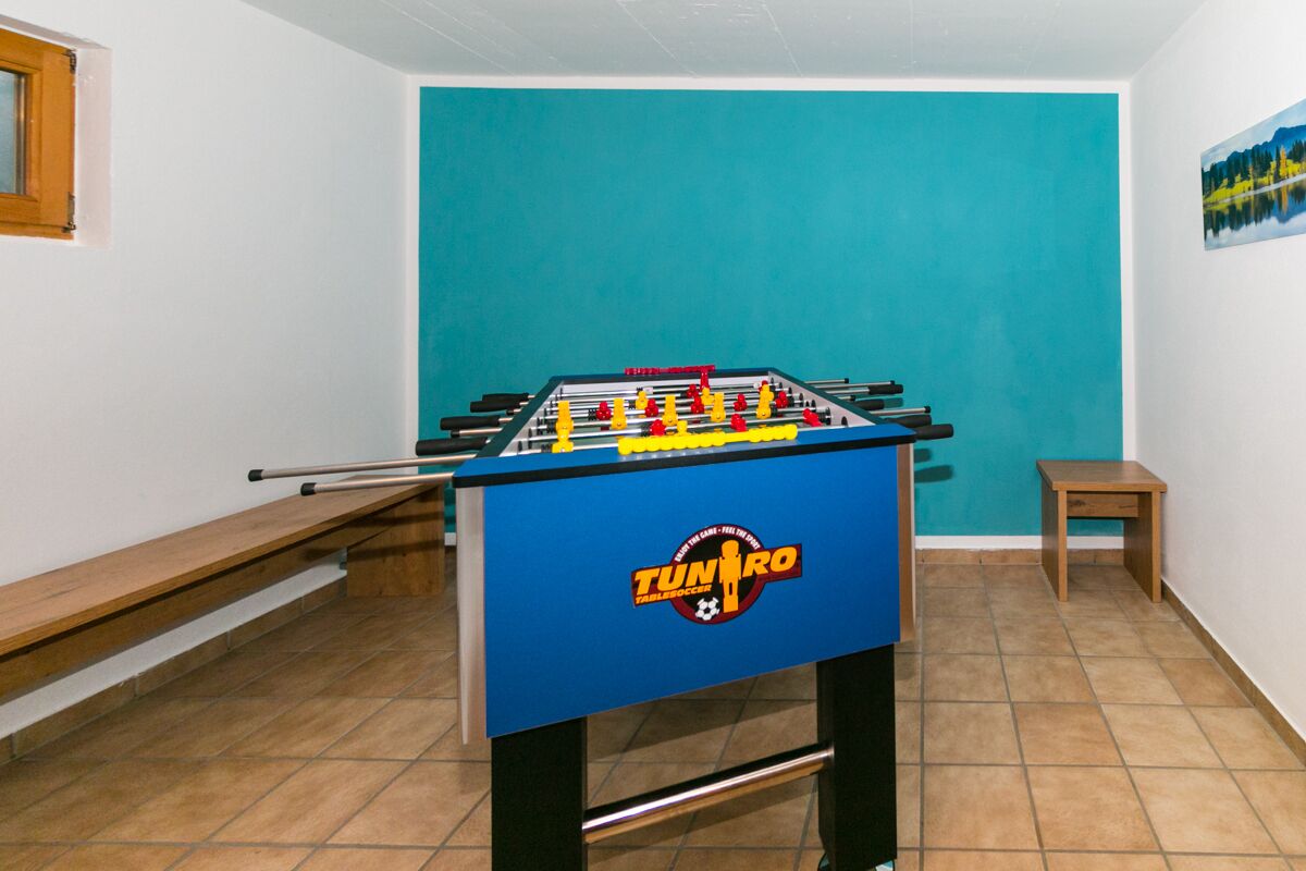 A foosball table in a room with a blue wall and a wooden bench.