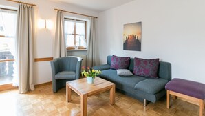 Olohuone, jossa on sohva, nojatuoli, puinen sohvapöytä ja penkki.