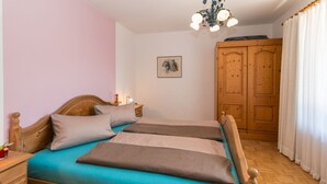 A double bed with a wooden headboard, a bedside table with a lamp, and a wardrobe with a mirror.