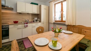 A compact kitchen with white cabinets, a wooden table, and a window with curtains.