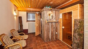 A wooden interior with a sauna, two wicker chairs, a wooden bench, a radiator, and a wooden door. - Dachgeschoss-Ferienwohnung (5) (Reit im Winkl)