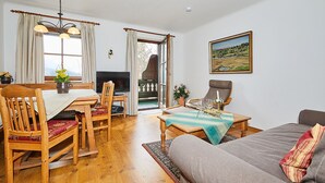 Un salon chaleureux avec une table à manger en bois, des chaises, un canapé et un téléviseur.