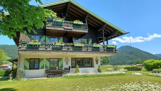 Un chalet traditionnel doté d’un balcon, d’un coin repas et offrant une vue sur le paysage environnant.