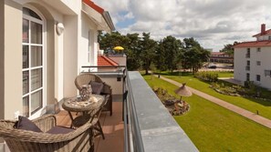 Ein Balkon mit Korbmöbeln, einem Tisch und einem gelben Sonnenschirm.