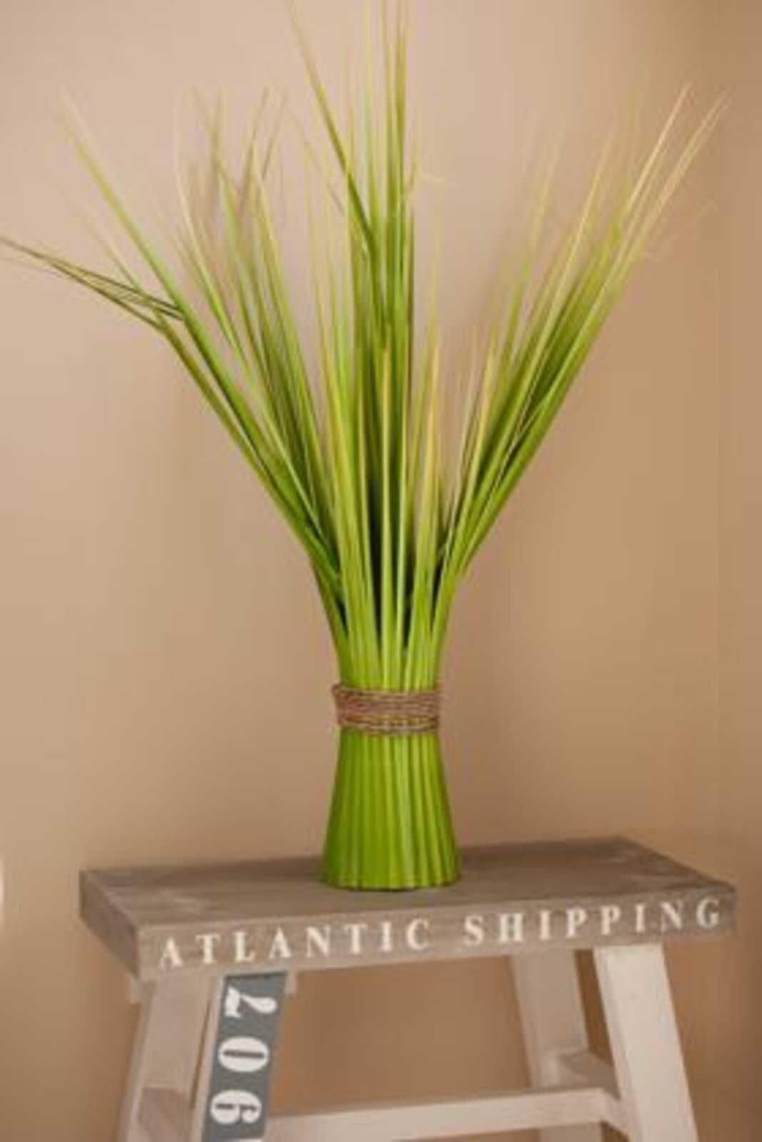 En grön vas med ett band på en vit pall där texten ”ATLANTIC SHIPPING” står.
