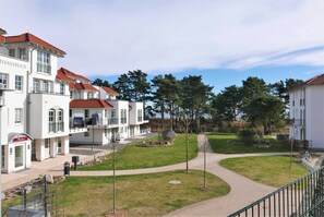 A hotel with a white facade, red-tiled roofs, and a landscaped courtyard with pathways.
