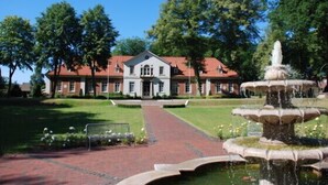 Ein Gebäude mit rotem Dach und einem Springbrunnen im Vordergrund.