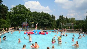 Ein öffentliches Schwimmbecken mit mehreren Bahnen, einer Sprungplattform und aufblasbaren Spielzeugen.