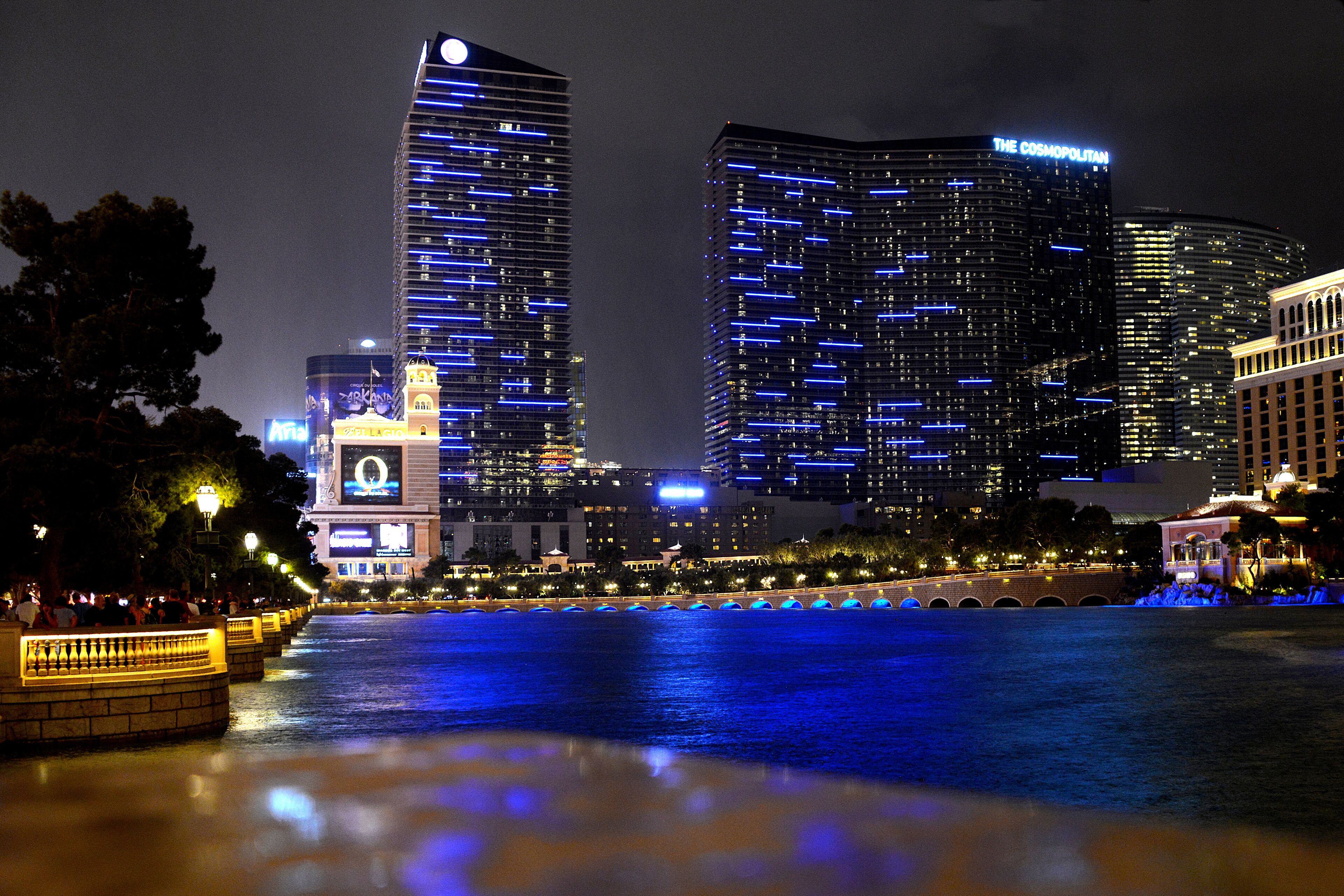 Une vue nocturne d’une ville, avec des gratte-ciel illuminés et une promenade en bord de mer.
