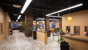 Un hall d’entrée doté d’un sol à motifs, d’un comptoir de réception, d’un espace détente et de plusieurs luminaires suspendus.