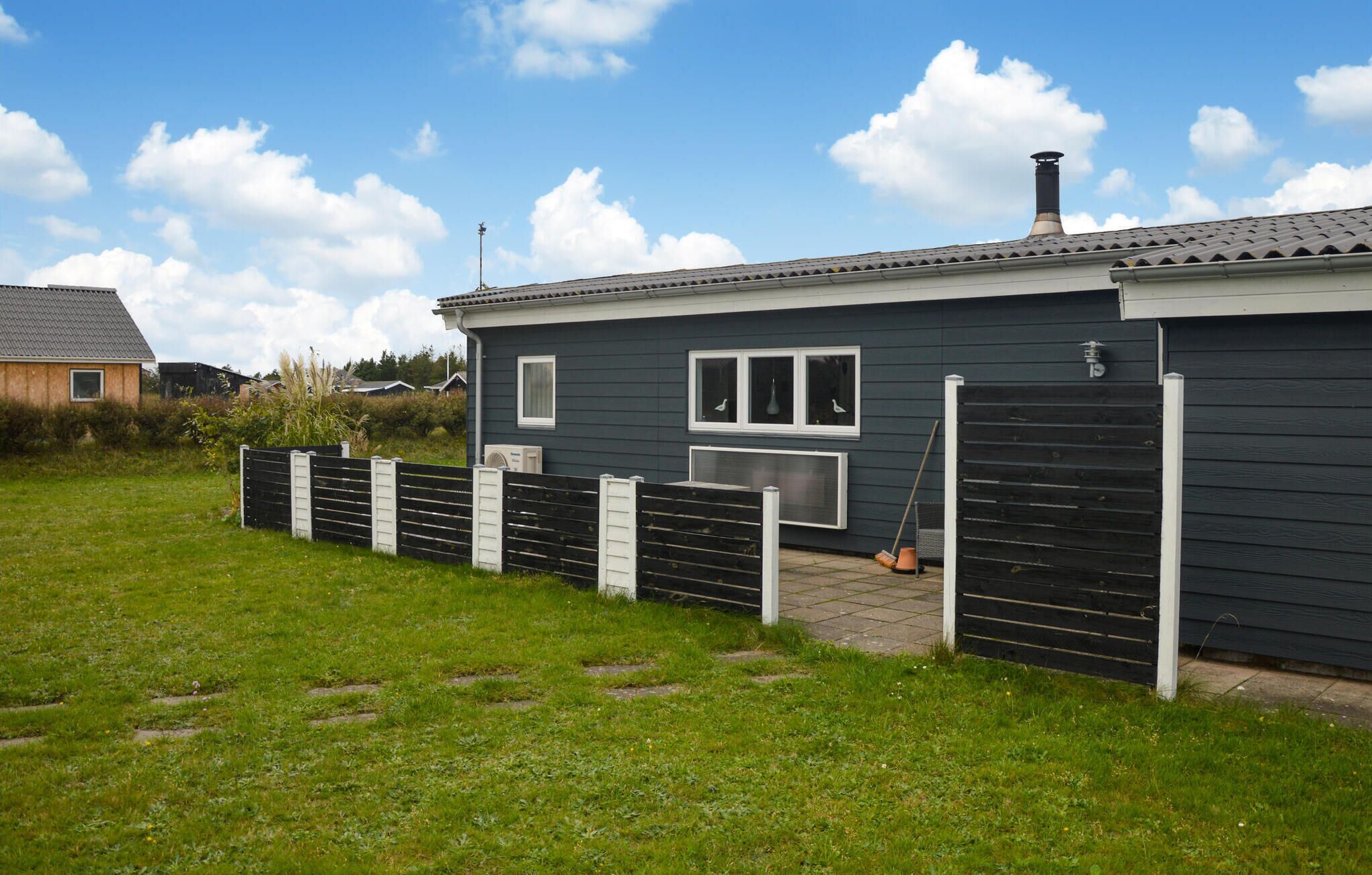 Et etagers hus med mørk facade, skorsten og en indhegnet gård.