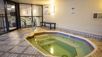 A swimming pool with a tiled floor, a bench, and a staircase leading to another area.