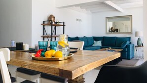Ein modernes Wohnzimmer mit einem Holzesstisch, einem blauen Sofa und einer Buddha-Kopf-Skulptur auf einem Regal.