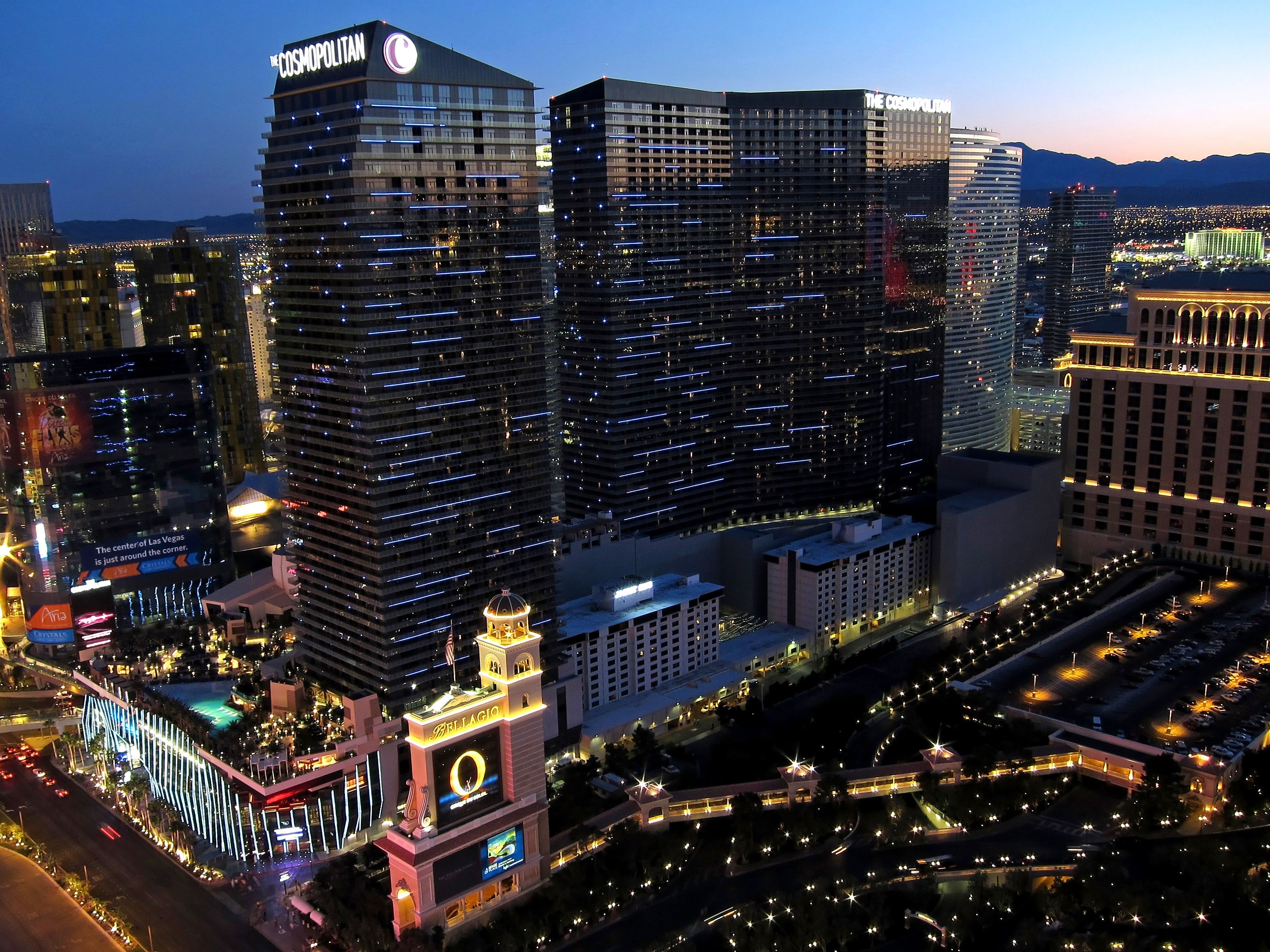 A high-rise hotel with multiple floors, a prominent sign, and a large illuminated structure nearby.