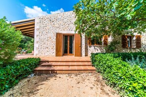 Un bâtiment en pierre avec une porte en bois et des marches menant à un patio.