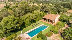 A villa with a swimming pool, surrounded by lush greenery and mountains.