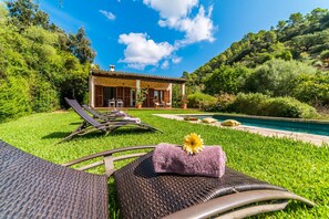 Une villa avec piscine, entourée d’une végétation luxuriante et sous un ciel d’un bleu éclatant.