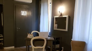 A room with a wooden floor, a desk with a computer, two chairs, a wall-mounted TV, and an air conditioning unit. - Casa Fornaretto (Venice)