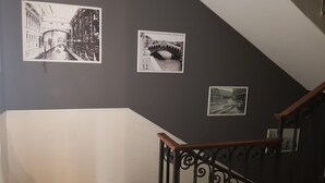A staircase with a dark wall and three black-and-white photographs. - Casa Fornaretto (Venice)