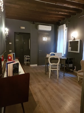 A room with a wooden ceiling, a desk with a computer, a chair, and a bookshelf with books.