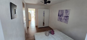 Een gang met een bed, een kledingkast en een deur naar een andere kamer.
