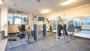 A gym with various exercise machines, large windows, and a carpeted floor. - Stay Together Suites | Cozy Strip Condo (Las Vegas)
