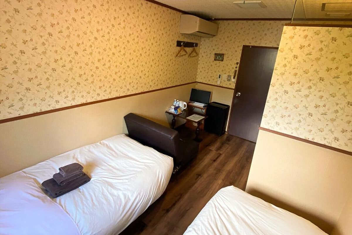 A small, cozy room with two single beds, a desk with a chair, and a wardrobe.