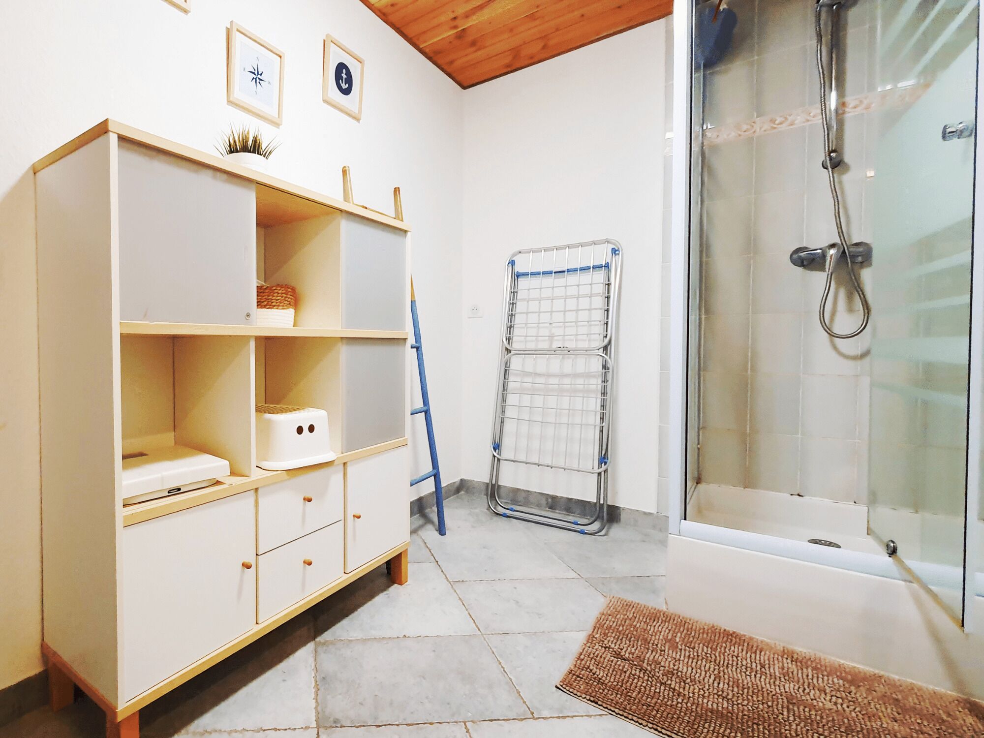 Een badkamer met een wit kastje, een douche en een handdoekrek.